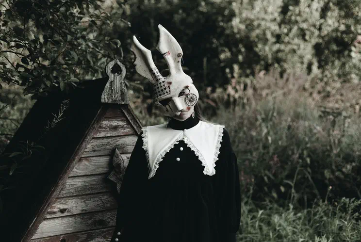 a person wearing a rabbit costume standing in front of a shed